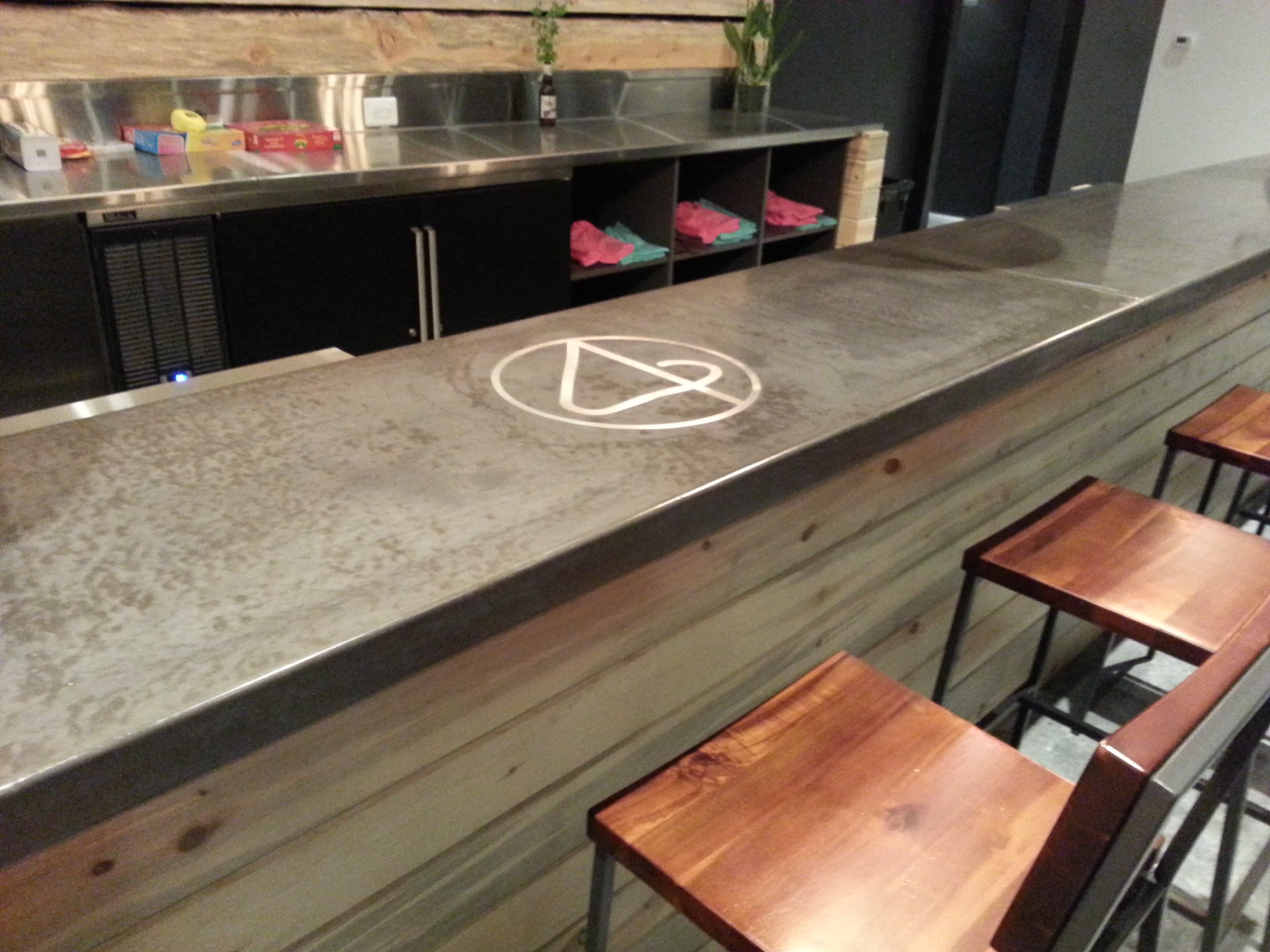 Charcoal concrete bar top with an inlaid brass-colored logo