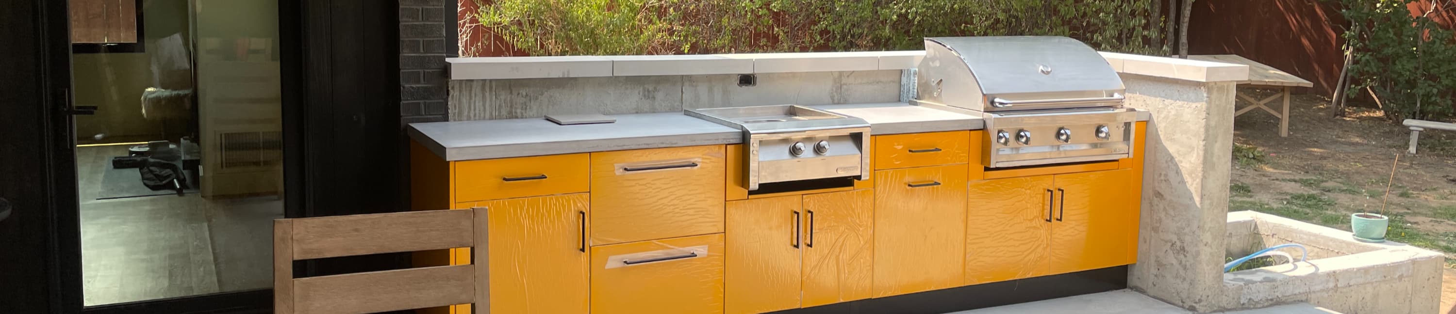 Outdoor kitchen with a pale grey concrete top beside a grill