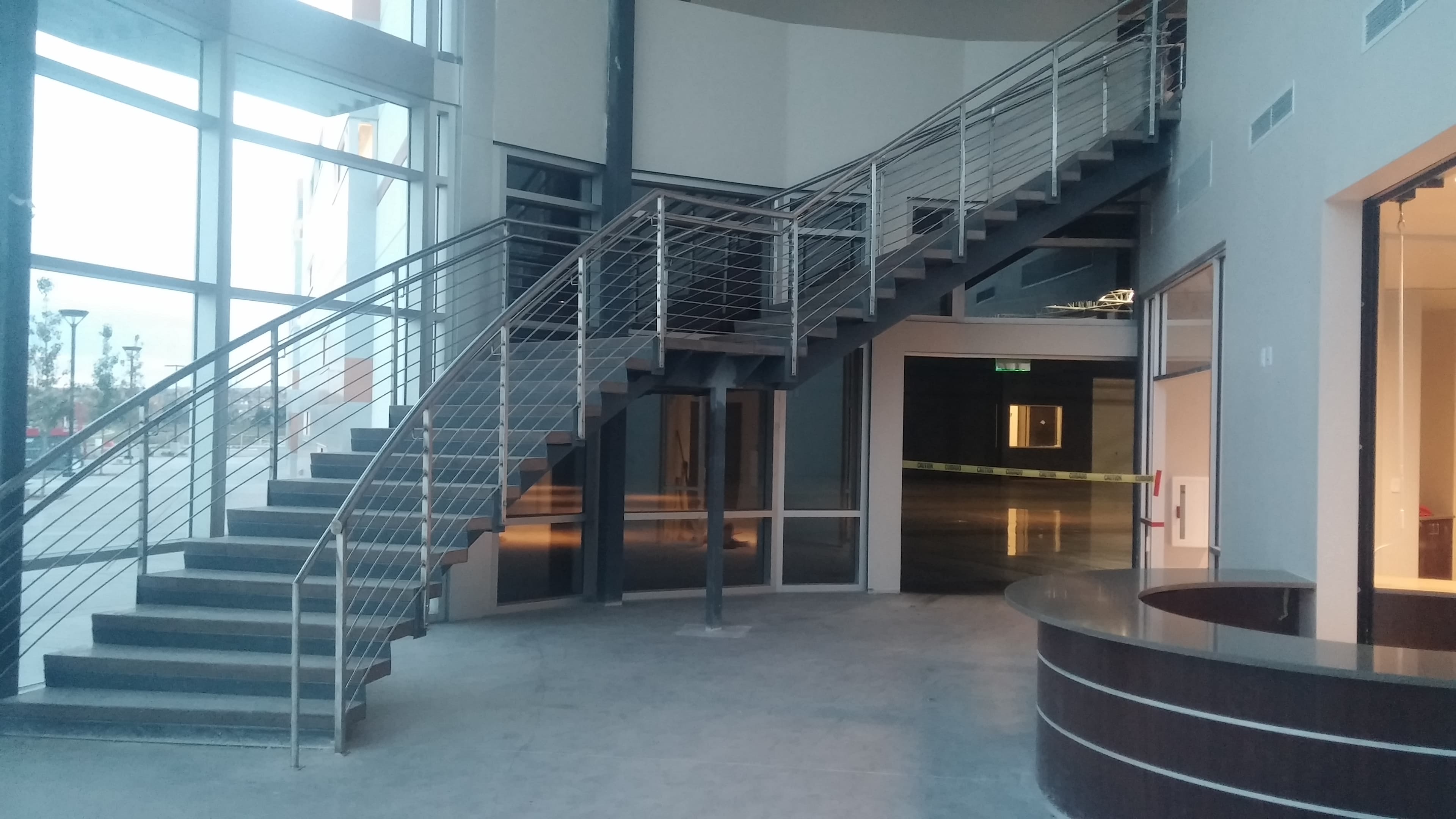 Curved concrete stair and round reception desk in an office lobby